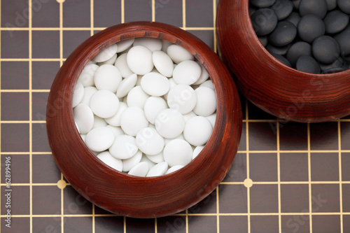 white go double convex yunzi stones in wooden bowl photo