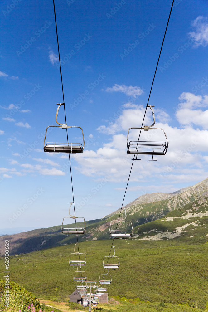 view on mountains in summer with ski lift on blue sky background view on mountains in summer with ski lift on blue sky background