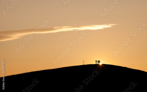 silhouette of people standing on hill in sunset