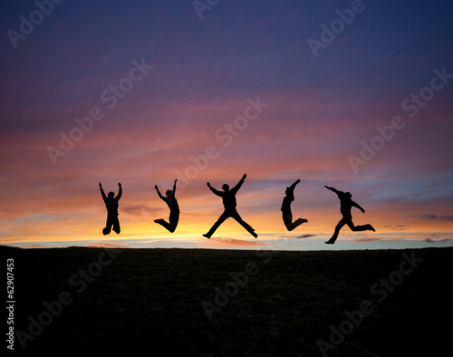 silhouetted teens jumping in sunset sky