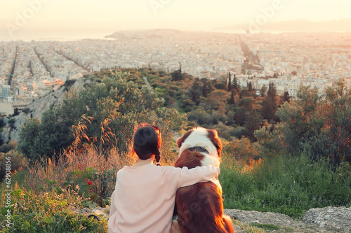 Young woman hugs her dog as they sit in a field.Athens,Greece.Re