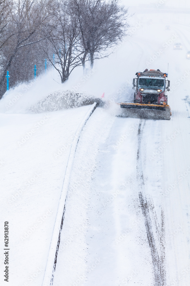 Snowplow removing the Snow from the Highway during a Snowstorm Snowplow removing the Snow from the Highway during a Snowstorm