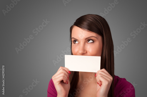 Cute girl holding white card at front of her lips with copy spac