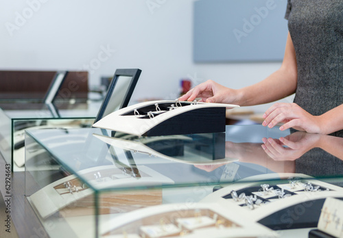 Hands of shop assistant at the window case with rings