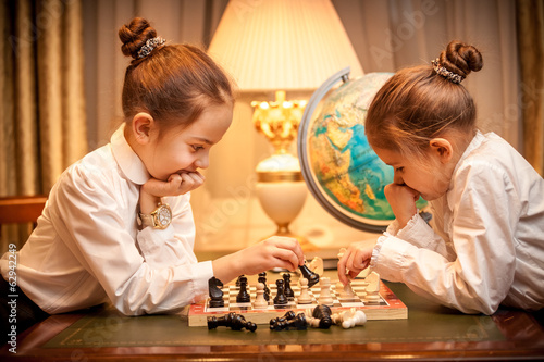 Two girls in school uniform playing chess at cabinet