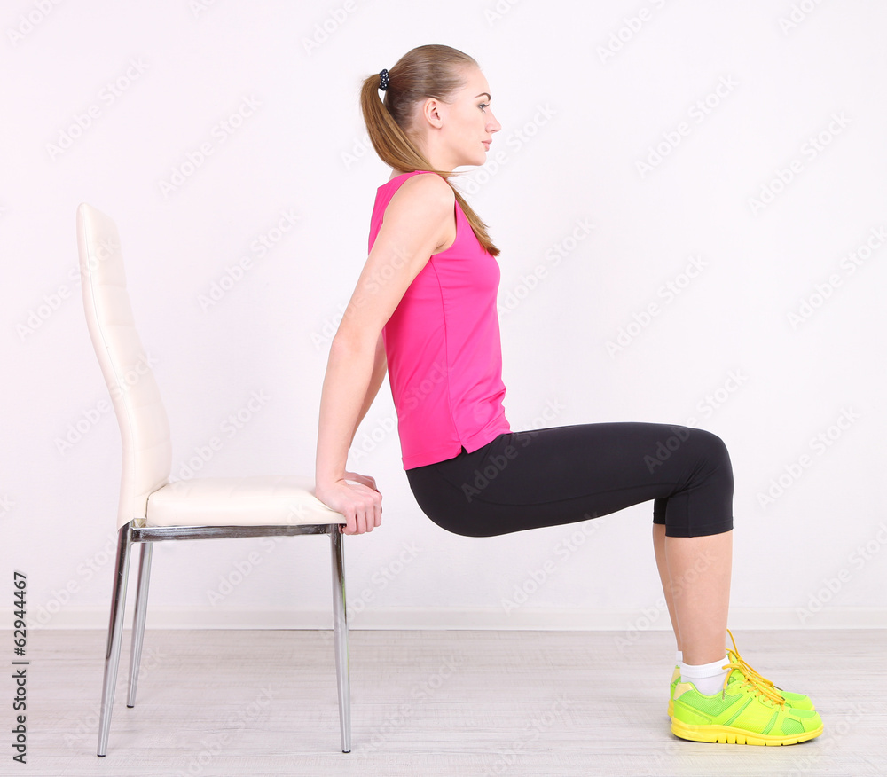 Young beautiful fitness girl exercising with chair in gym Young beautiful fitness girl exercising with chair in gym