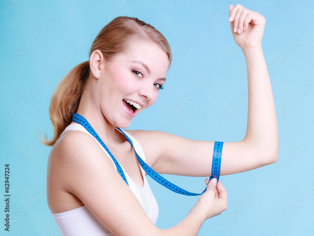 Fitness girl sporty woman measuring her biseps on blue Fitness girl sporty woman measuring her biseps on blue