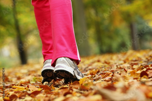 Runner legs running shoes. Woman jogging in autumn park