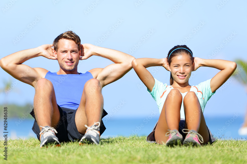 Sit ups - fitness couple exercising sit up outside Sit ups - fitness couple exercising sit up outside