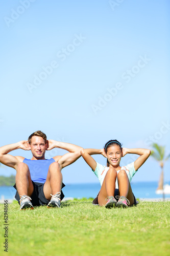 People exercising - Couple doing sit ups outdoors