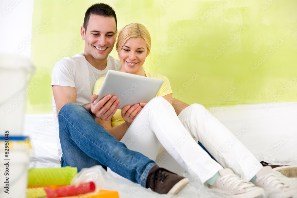 couple using tablet while painting home couple using tablet while painting home