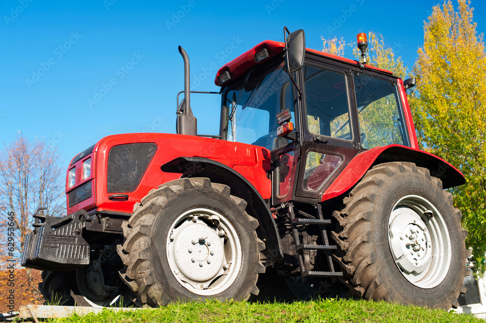 Modern red tractor on a blue sky background Modern red tractor on a blue sky background
