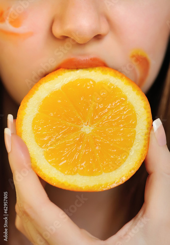 Young beautiful woman eating an orange