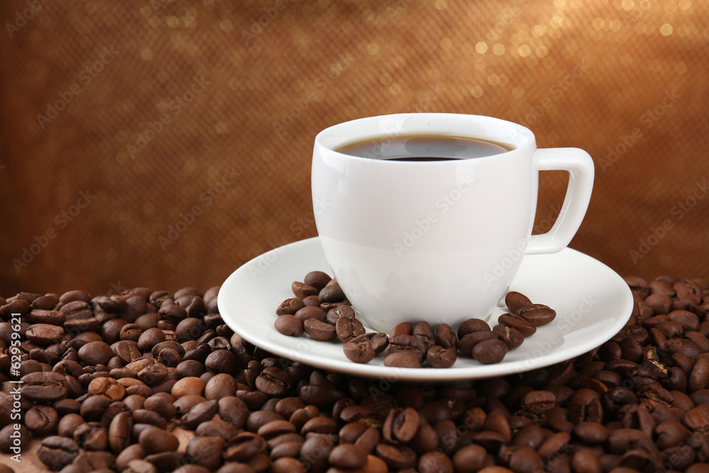 Coffee beans and cup of coffee on table on brown background Coffee beans and cup of coffee on table on brown background