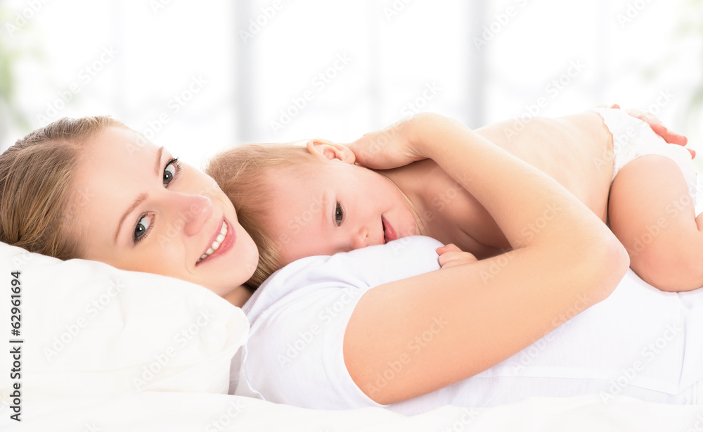 happy family mother and baby having fun playing, laughing on bed happy family mother and baby having fun playing, laughing on bed