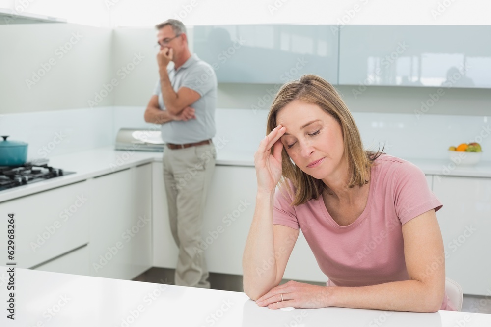 Couple not talking after an argument in kitchen Couple not talking after an argument in kitchen