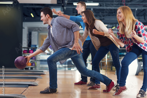 Print op canvas Friends cheering their friend while throwing bowling ball