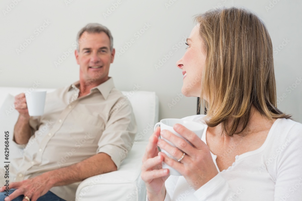 Relaxed couple with coffee cups in living room Relaxed couple with coffee cups in living room