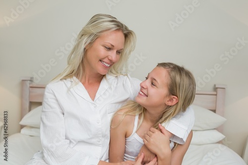 Mother and daughter looking at each other in bed