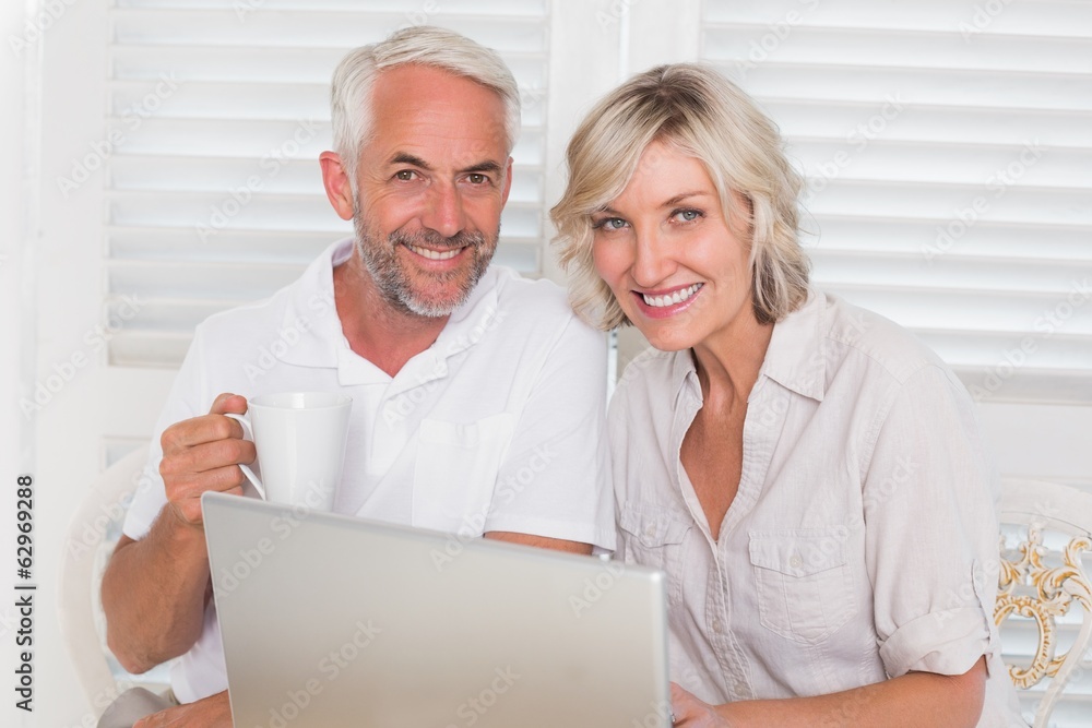 Smiling mature couple using laptop at home Smiling mature couple using laptop at home