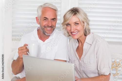 Smiling mature couple using laptop at home