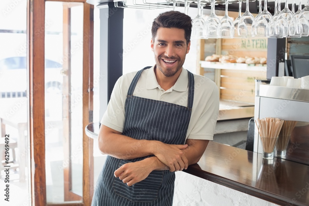 Fototapeta premium Portrait of a smiling young waiter at cafe counter