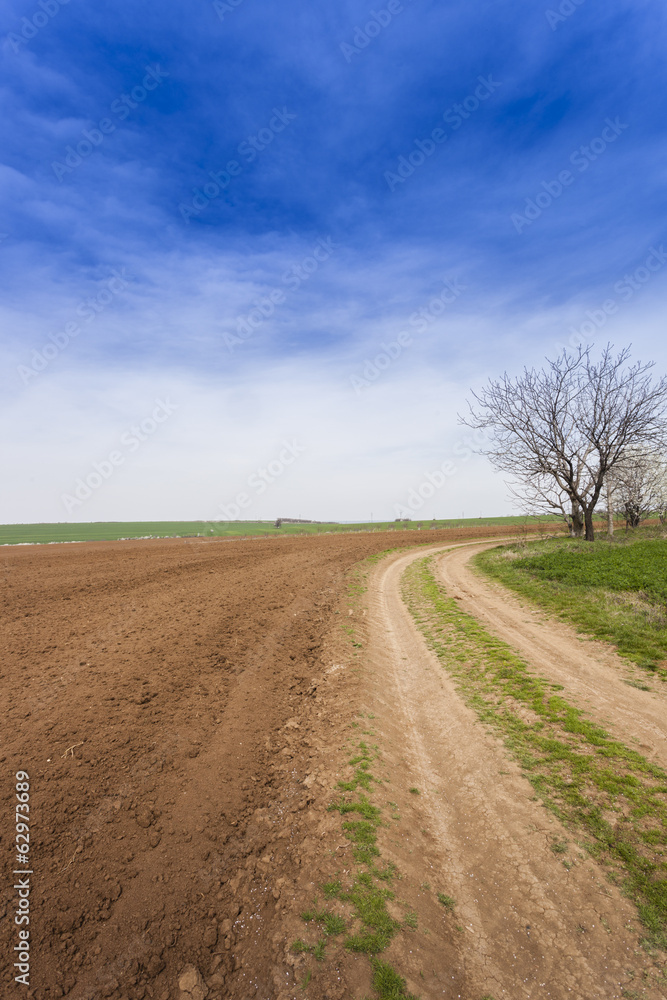 Ploughed field under deep blue sky with clouds