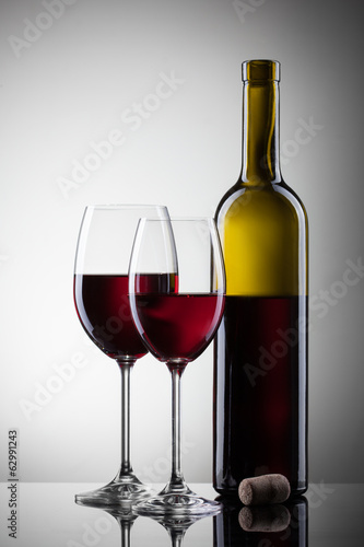 Wine in glasses and bottle on white