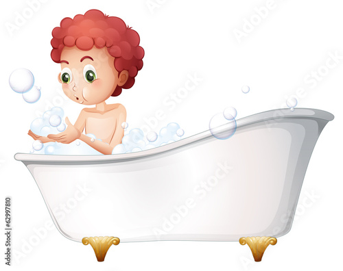 A young boy playing at the bathtub while taking a bath