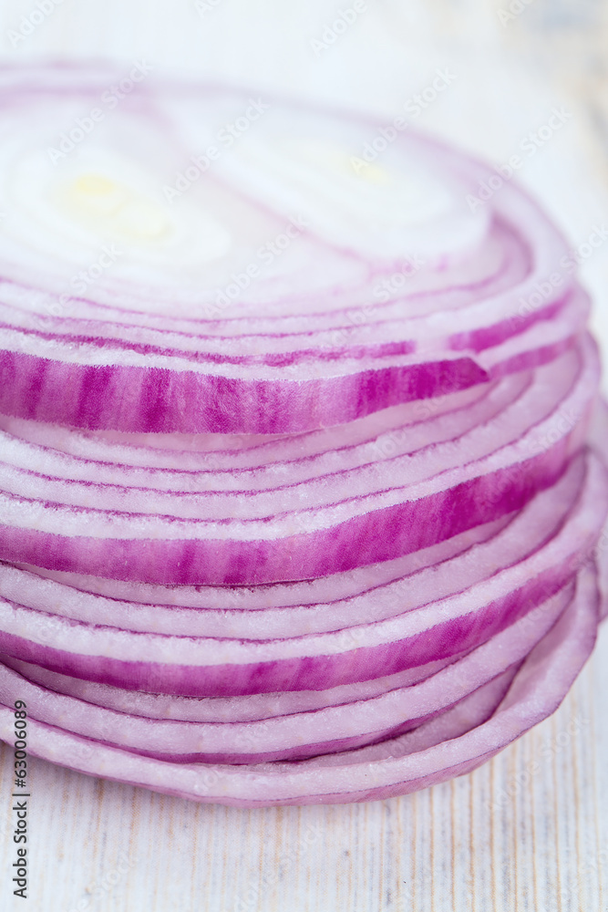 slices of red onions on white wooden surface slices of red onions on white wooden surface