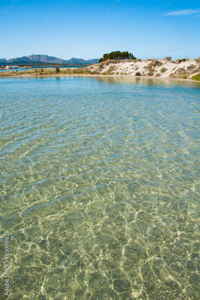 A crystal-clear water with a sand dune on background, Sardinia