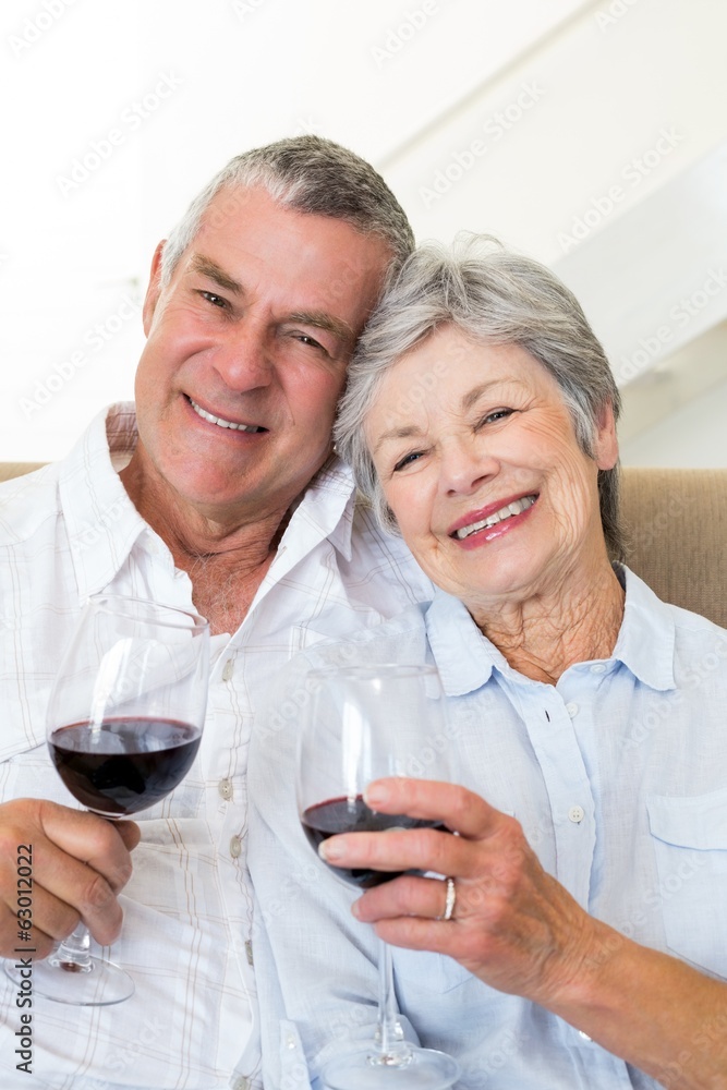 Senior couple sitting on couch having of red wine Senior couple sitting on couch having of red wine