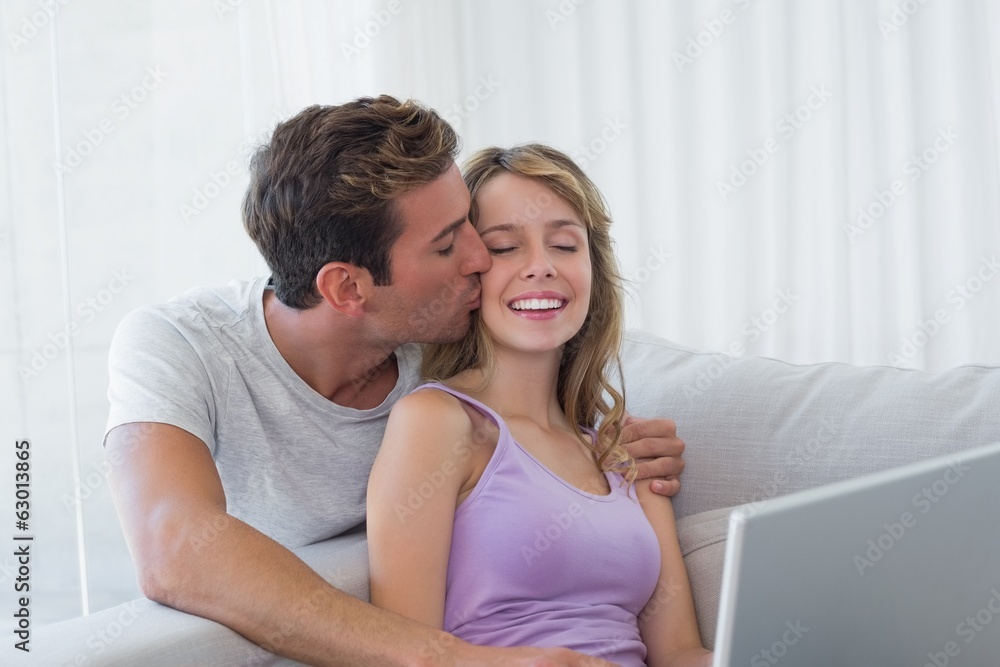 Loving young couple using laptop on couch