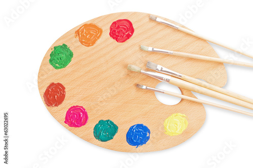 wooden art palette with paint and brushes, close up