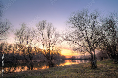 Old country road on lake at the autumn sunset light