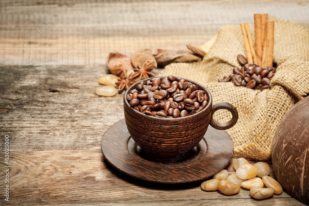 Wooden cup with coffee-beans on wooden table Wooden cup with coffee-beans on wooden table