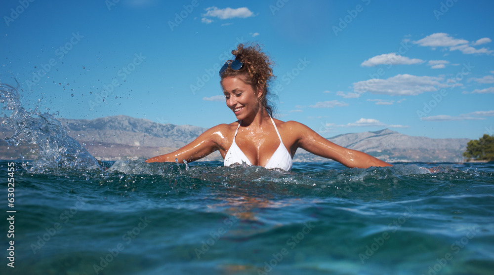 Beautiful swimsuit model splashing water on vacation