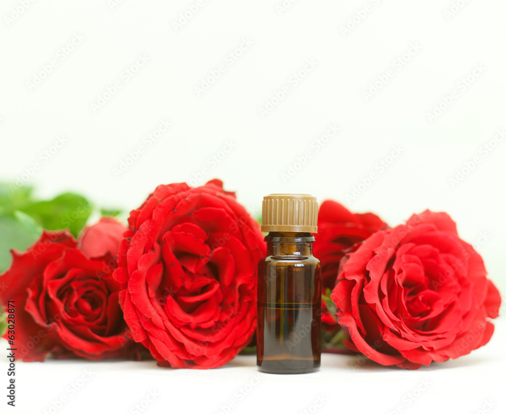 bottle of aromatherapy oil and bright red roses, beauty spa bottle of aromatherapy oil and bright red roses, beauty spa