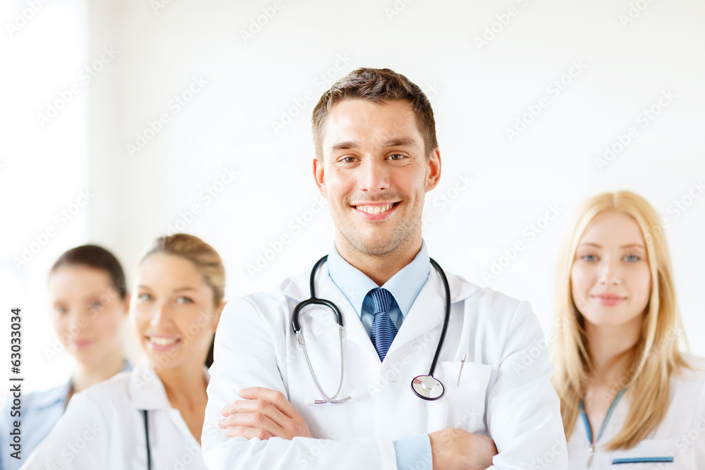 smiling male doctor in front of medical group smiling male doctor in front of medical group