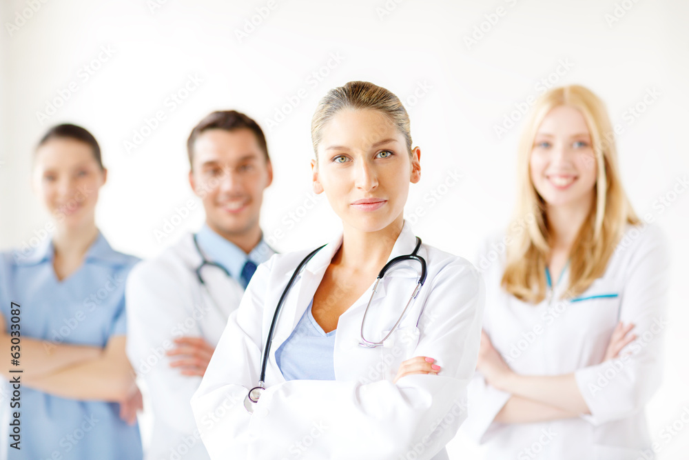 serious female doctor in front of medical group serious female doctor in front of medical group