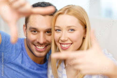 smiling happy couple making frame gesture at home