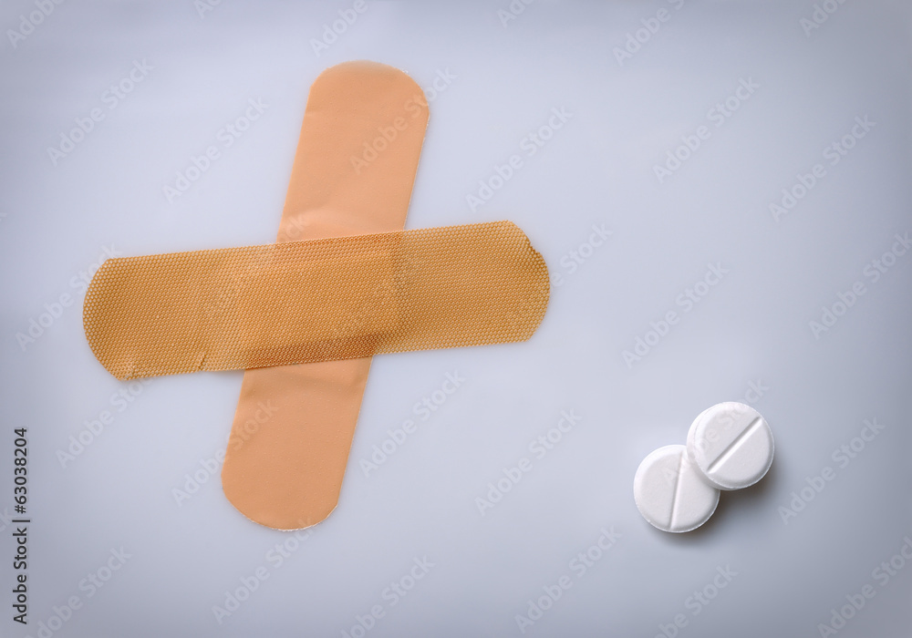 two bandaids and two pills on a table two bandaids and two pills on a table