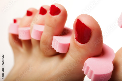 foot pedicure applying red toenails on white