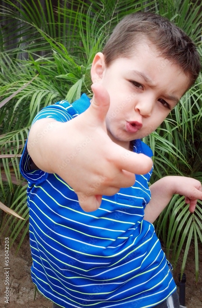 cute mixed-race young boy holds a thumbs up outside. cute mixed-race young boy holds a thumbs up outside.