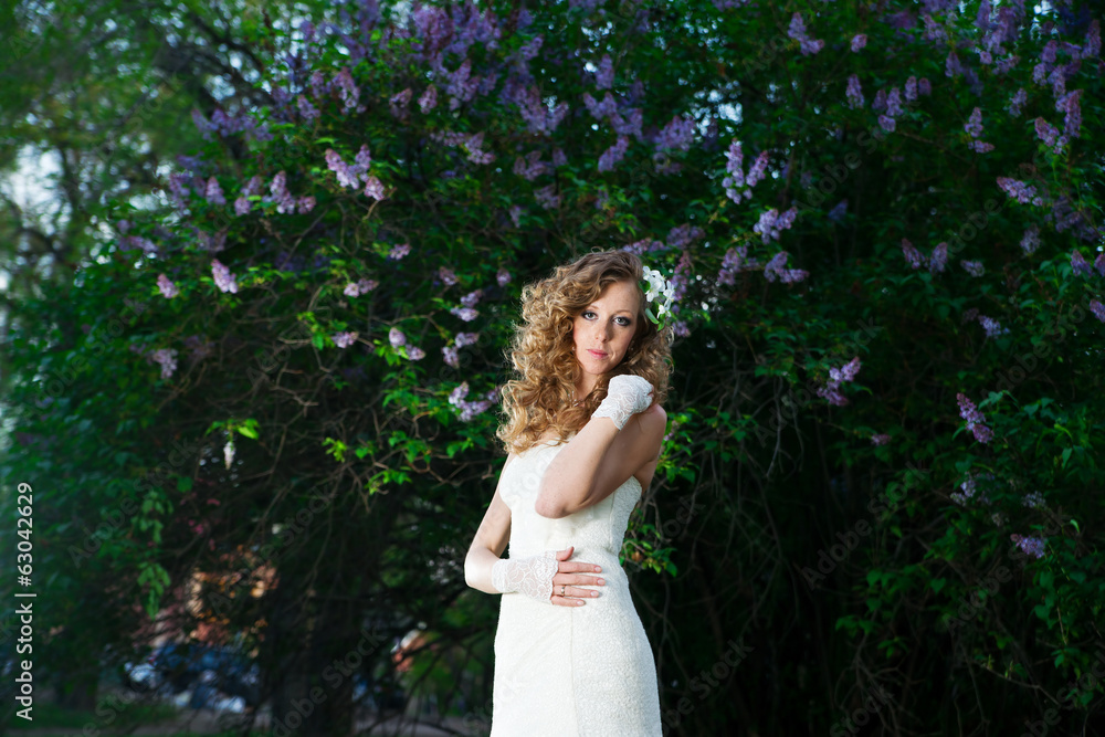 Beautiful bride in a white dress on a lilac background in spring