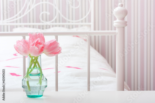 Pink tulips flowers in vase in a bedroom.