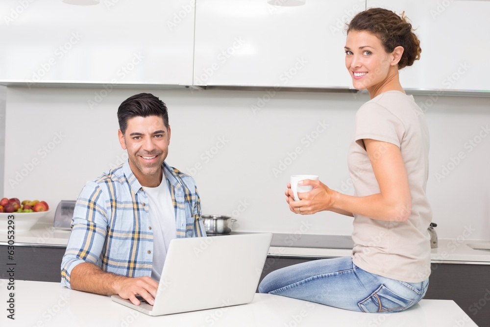 Obraz premium Smiling man using laptop while partner sits with a coffee
