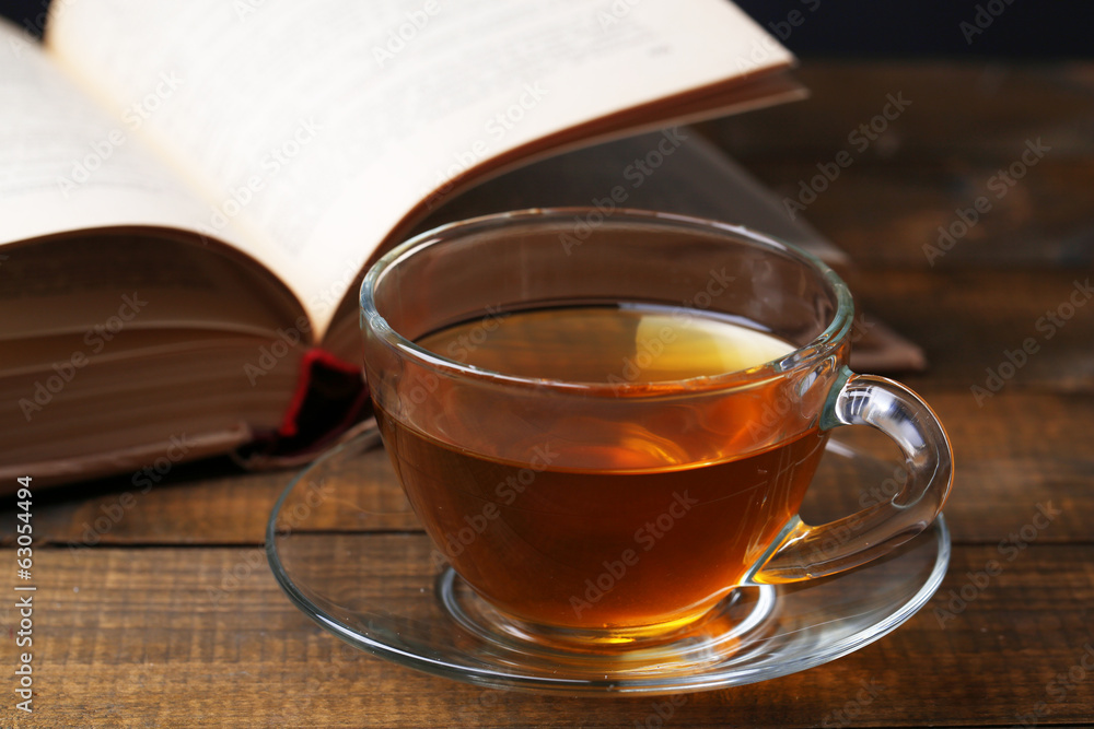 Cup of hot tea with book on wooden background Cup of hot tea with book on wooden background