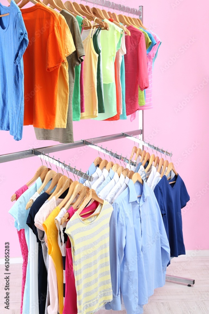 Different clothes on hangers, on pink background