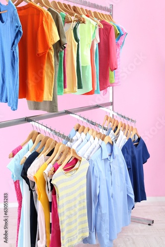 Different clothes on hangers  on pink background